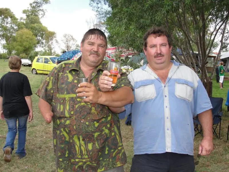 Twee familielede lig 'n glas vir die kamera by 'n familiebyeenkoms